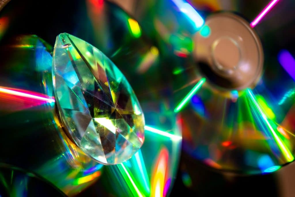 Colorful abstract image of a crystal prism and CDs reflecting rainbow colors.