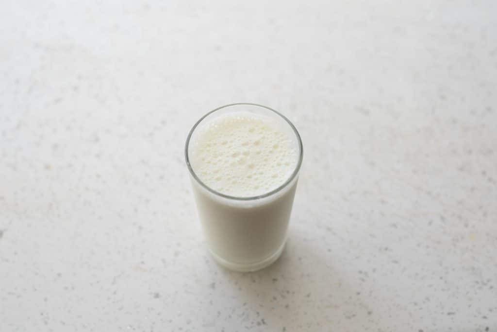 A top-down view of a foamy glass of milk on a white marble surface. Perfect for a healthy lifestyle concept.
