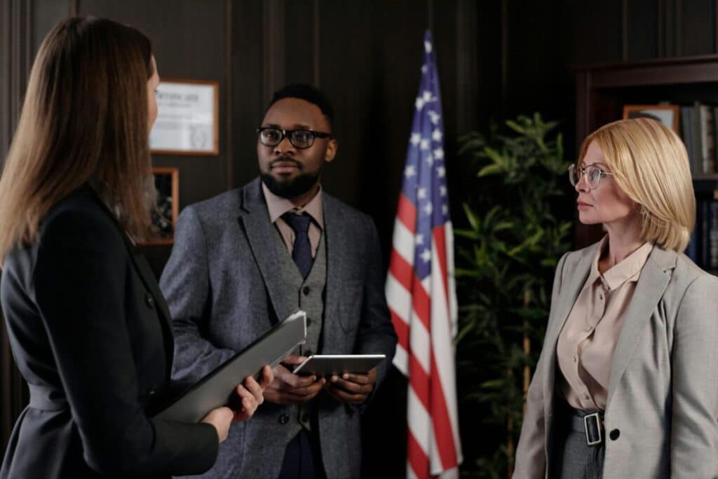 A group of business professionals discussing in an office with a USA flag.