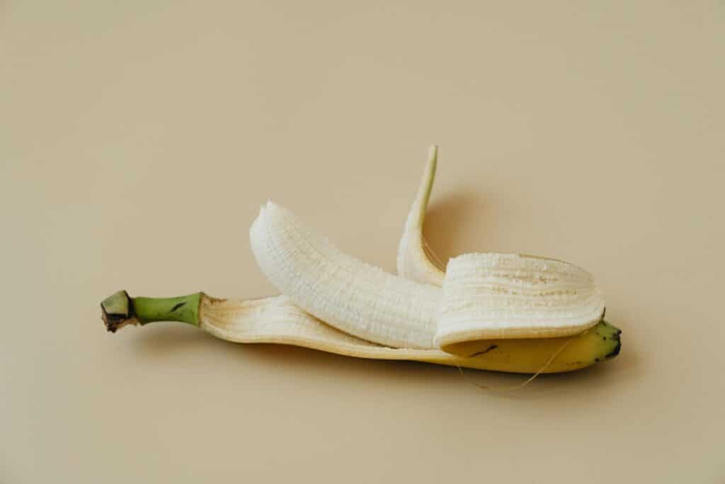 A peeled banana displayed on a soft beige background in a minimalist style.