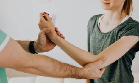 Image of a physiotherapy session focusing on arm movement and manual adjustment.