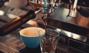 Espresso dripping into a glass cup from a metallic machine, capturing coffee essence.