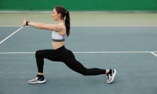 Woman in activewear stretching on a tennis court, focusing on fitness and flexibility.
