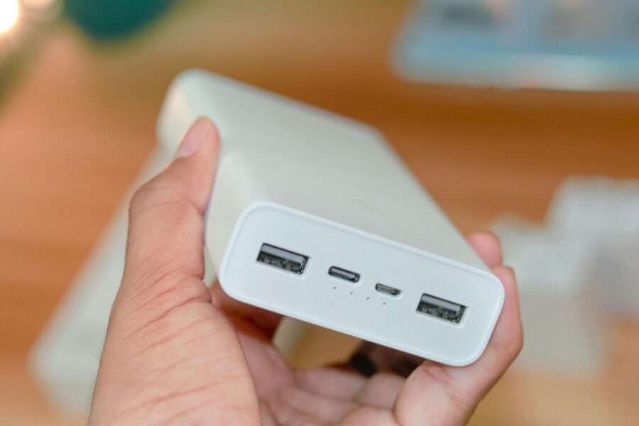 Hand holding a powerbank showcasing its USB ports on a wooden background.