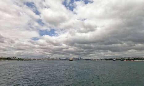 Cloudy sky view of Istanbul's Bosphorus Strait with city skyline in distance.