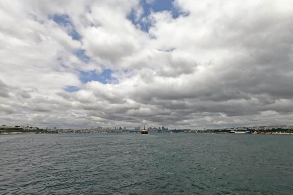Cloudy sky view of Istanbul's Bosphorus Strait with city skyline in distance.