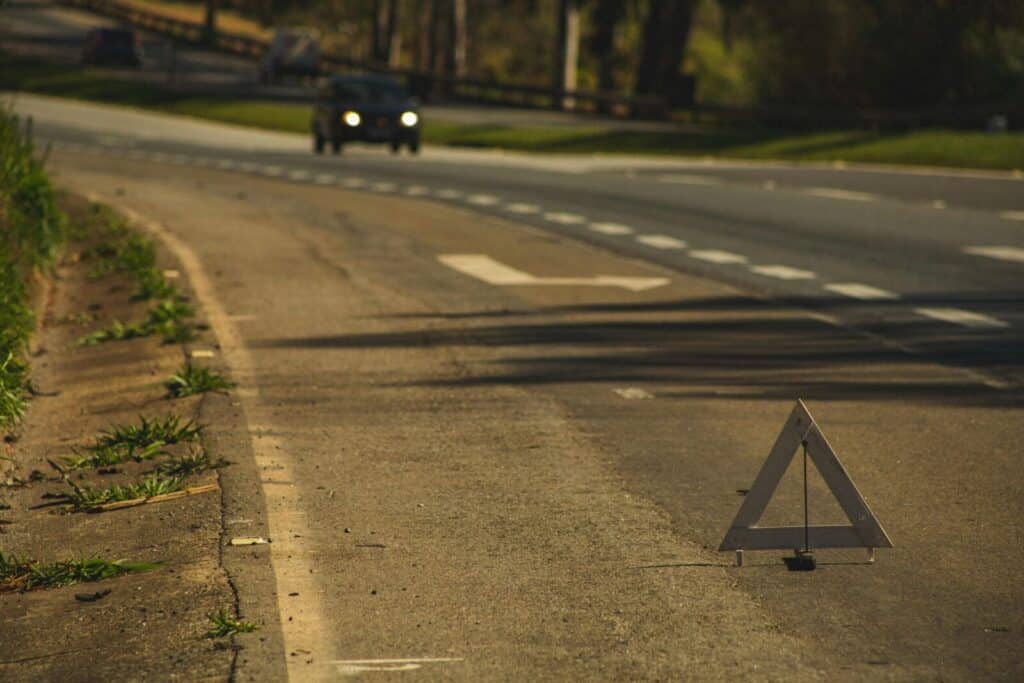 A roadside emergency triangle placed on an empty asphalt road, indicating caution.