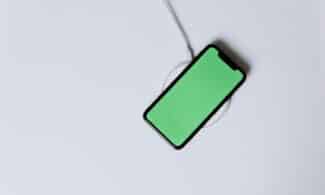 Overhead view of a smartphone with a green screen on a wireless charger, showcasing modern technology.