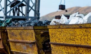 Close-up of rusty mining carts filled with various minerals in an industrial setting.