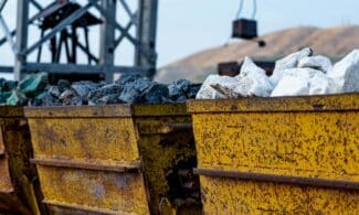 Close-up of rusty mining carts filled with various minerals in an industrial setting.