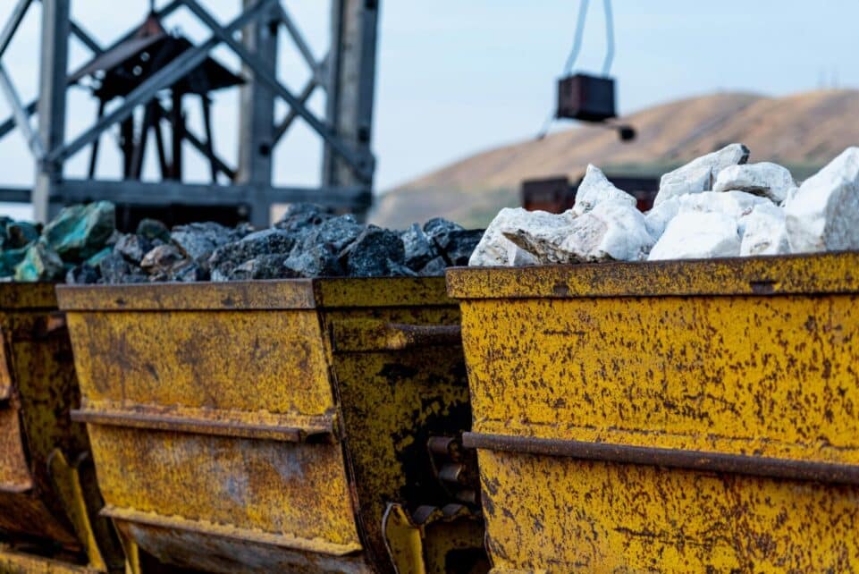 Close-up of rusty mining carts filled with various minerals in an industrial setting.