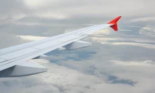 View from a plane window showing the wing against a cloudy sky.
