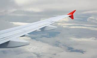 View from a plane window showing the wing against a cloudy sky.
