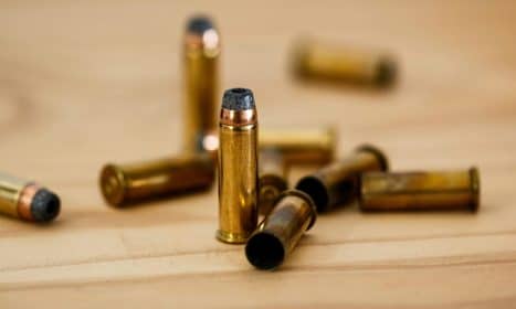 Detailed view of brass bullet shells scattered on a wood background.