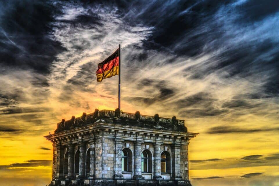 Vibrant sunset over a historic Berlin monument with the German flag waving.