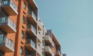 Contemporary apartment building with glass balconies under a clear blue sky.