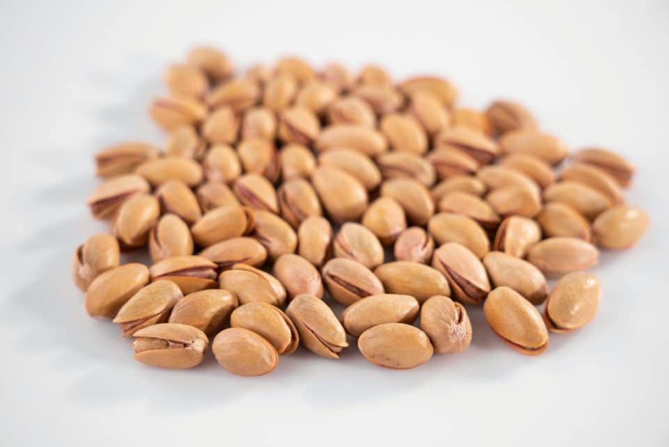 A close-up view of scattered pistachios on a white background, emphasizing texture.