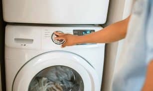Close-up of a person adjusting a washing machine in a modern laundry room.