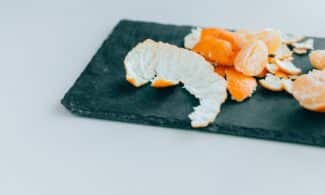 Close-up of peeled mandarins on a dark slate board, displaying freshness and vibrant color.