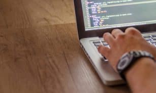 Close-up of a person coding on a laptop, showcasing web development and programming concepts.