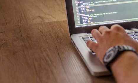 Close-up of a person coding on a laptop, showcasing web development and programming concepts.