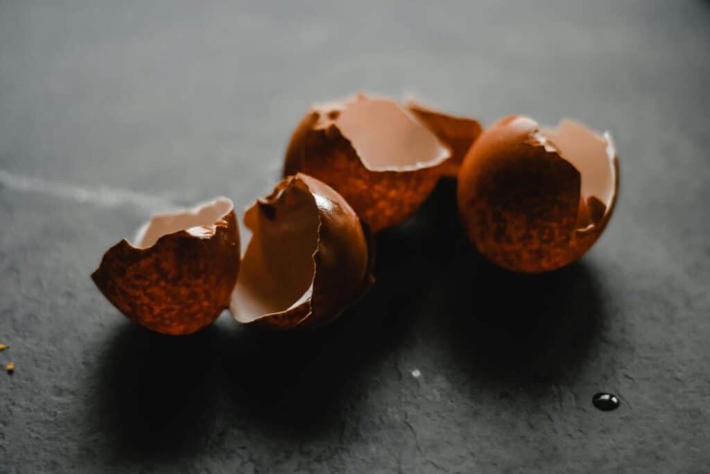 Macro shot of broken brown eggshells on a dark backdrop, perfect for culinary themes.