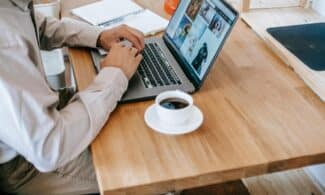 A person working on a laptop while enjoying a coffee at home, depicting a casual and productive workspace.