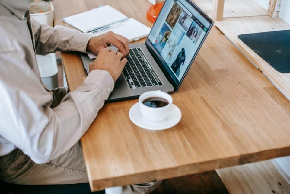 A person working on a laptop while enjoying a coffee at home, depicting a casual and productive workspace.