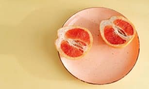 Close-up of a fresh grapefruit halved on a pink plate. Ideal for healthy eating concepts.