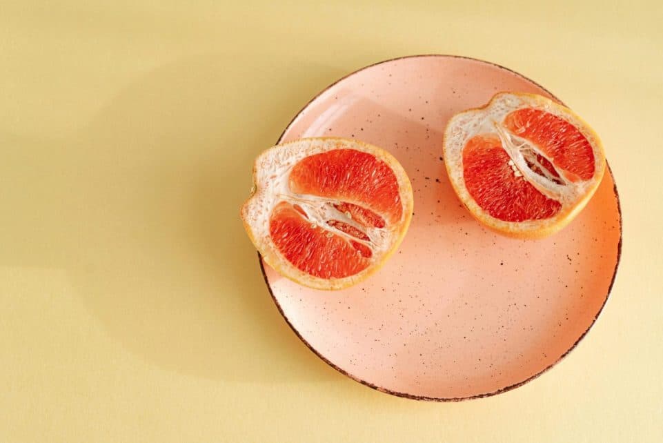 Close-up of a fresh grapefruit halved on a pink plate. Ideal for healthy eating concepts.