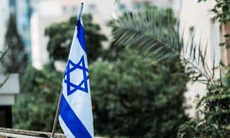 Israeli flag displayed among urban greenery, reflecting national pride and identity.