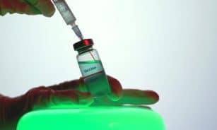 Syringe drawing vaccine from vial, symbolizing immunization efforts.