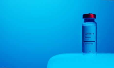 A COVID-19 vaccine vial with clear labeling on a serene blue background, symbolizing hope and health.