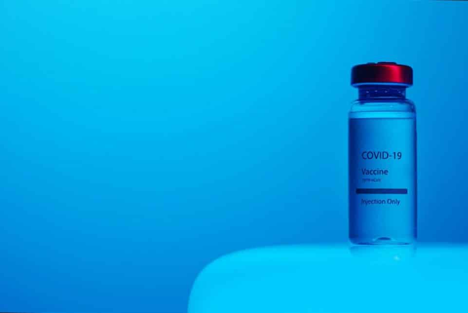 A COVID-19 vaccine vial with clear labeling on a serene blue background, symbolizing hope and health.