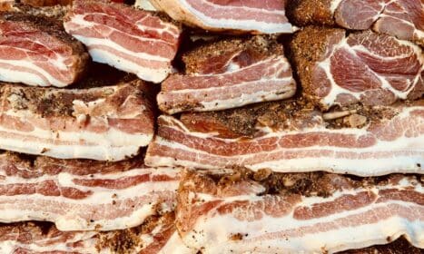 High-quality image of stacked raw pork belly slices, seasoned and ready for cooking.