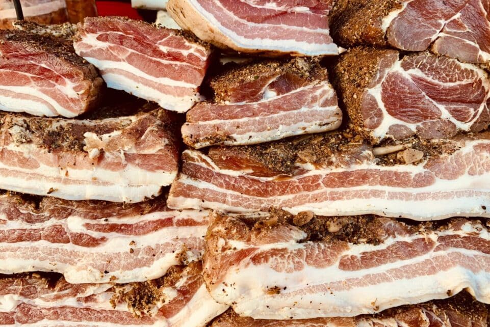 High-quality image of stacked raw pork belly slices, seasoned and ready for cooking.