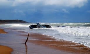 Dramatic view of a shipwreck on a stormy Sicilian beach, showcasing the power of nature.
