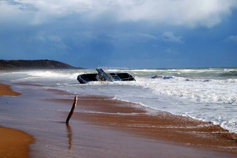 Dramatic view of a shipwreck on a stormy Sicilian beach, showcasing the power of nature.