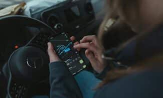 Person using GPS navigation app on smartphone inside car for directions.