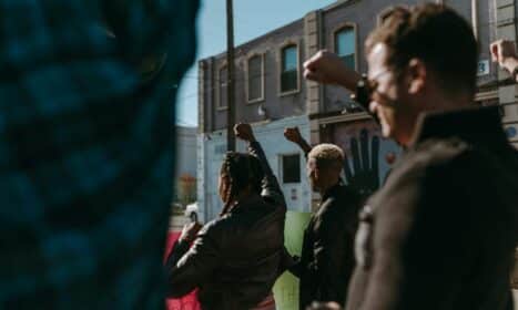 Protesters raising fists during a demonstration in an urban street setting, showing unity and diversity.