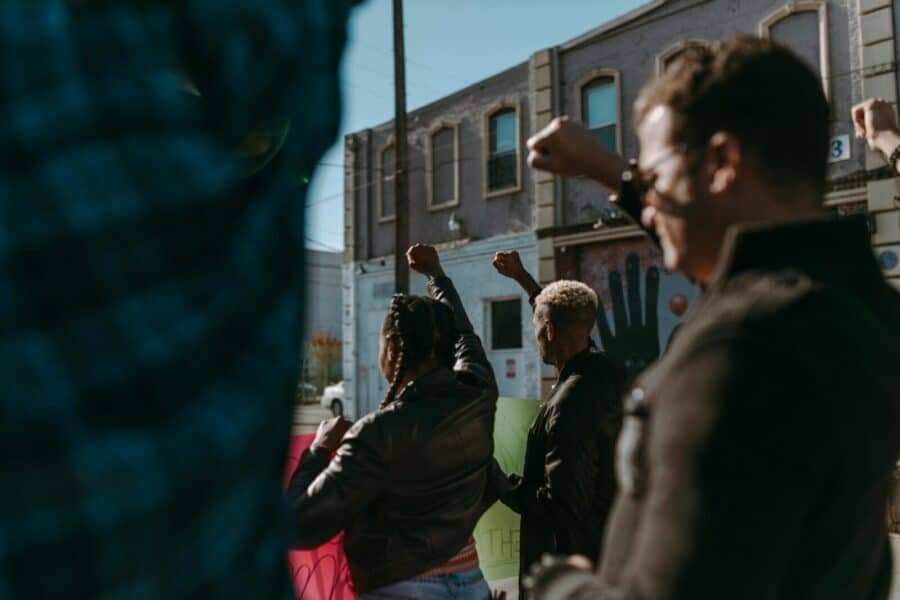 Protesters raising fists during a demonstration in an urban street setting, showing unity and diversity.