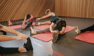 People stretching on exercise mats in an indoor gym during a workout session.