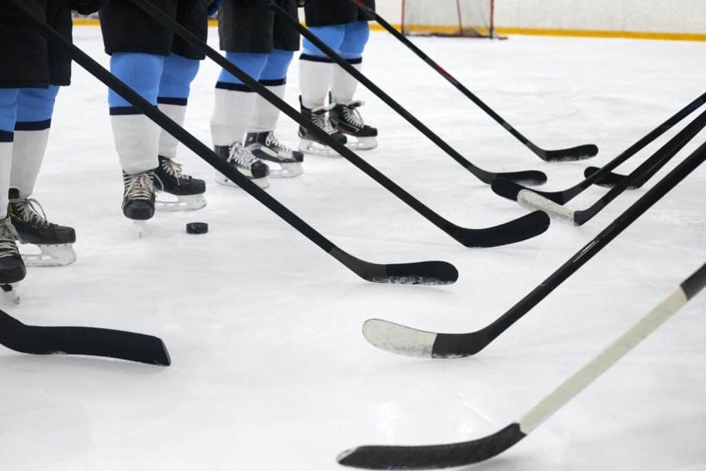 Close-up of hockey players on ice with sticks ready for a faceoff.