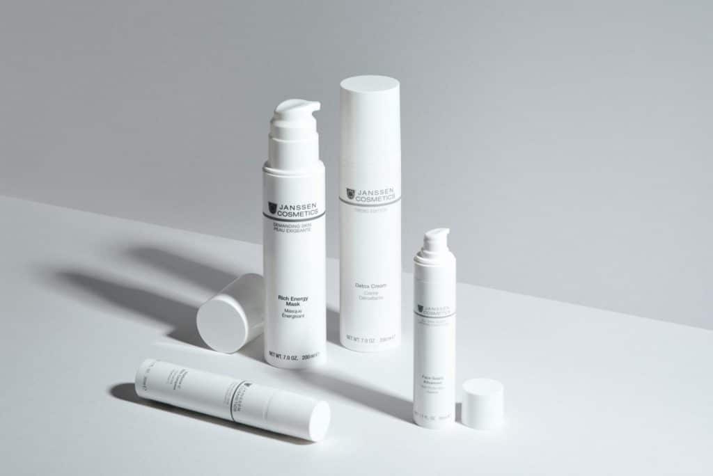 A minimalistic display of skincare bottles showcasing Janssen Cosmetics with a clean white backdrop.
