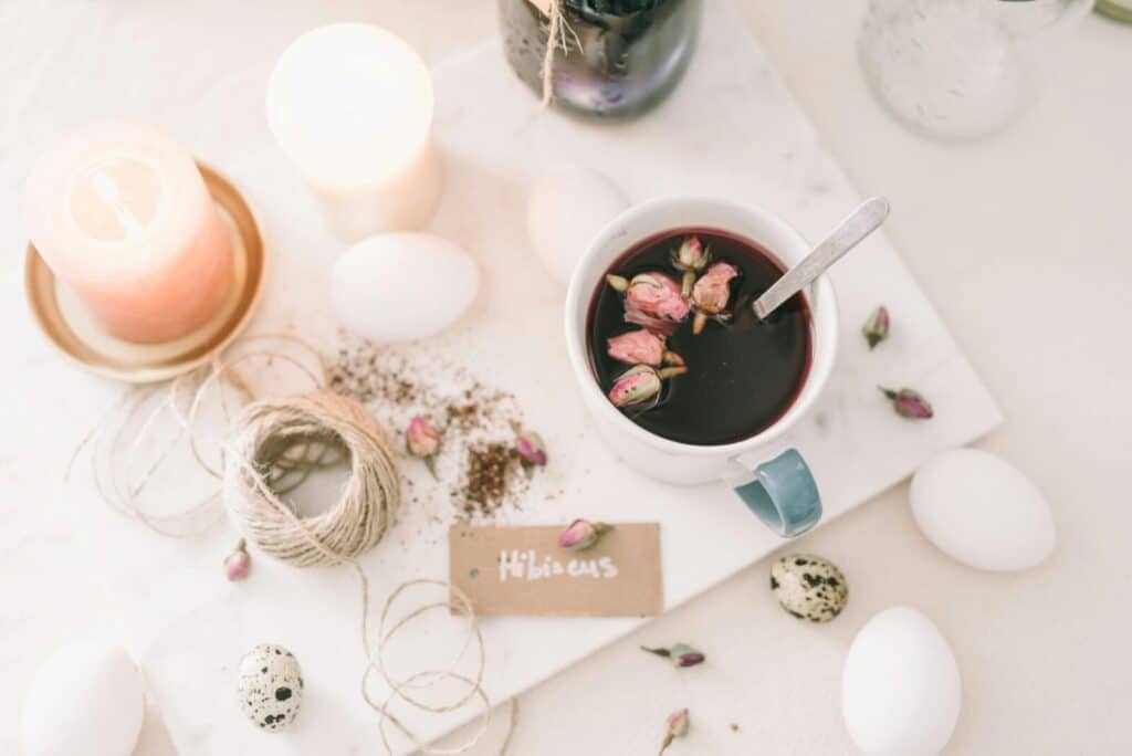 A serene flatlay featuring hibiscus tea, candles, and eggs, perfect for spring celebrations.