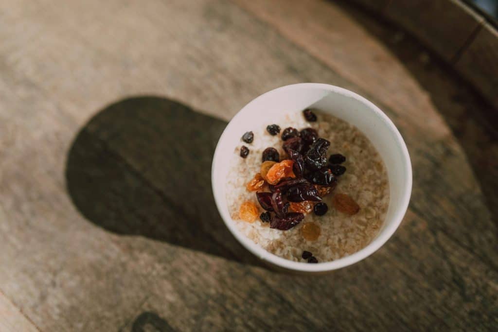A nutritious bowl of oatmeal topped with a variety of dried fruits photographed from above.