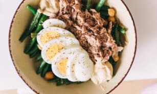 Delicious protein-packed bowl featuring tuna, boiled eggs, green beans, and hummus.