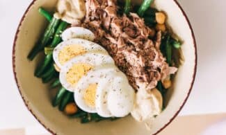Delicious protein-packed bowl featuring tuna, boiled eggs, green beans, and hummus.