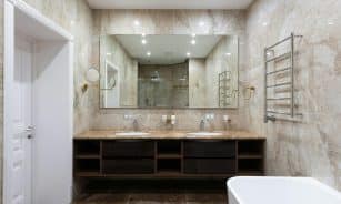 Interior of contemporary bathroom with marble walls and white clean sinks under bright glowing lamps