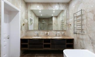 Interior of contemporary bathroom with marble walls and white clean sinks under bright glowing lamps